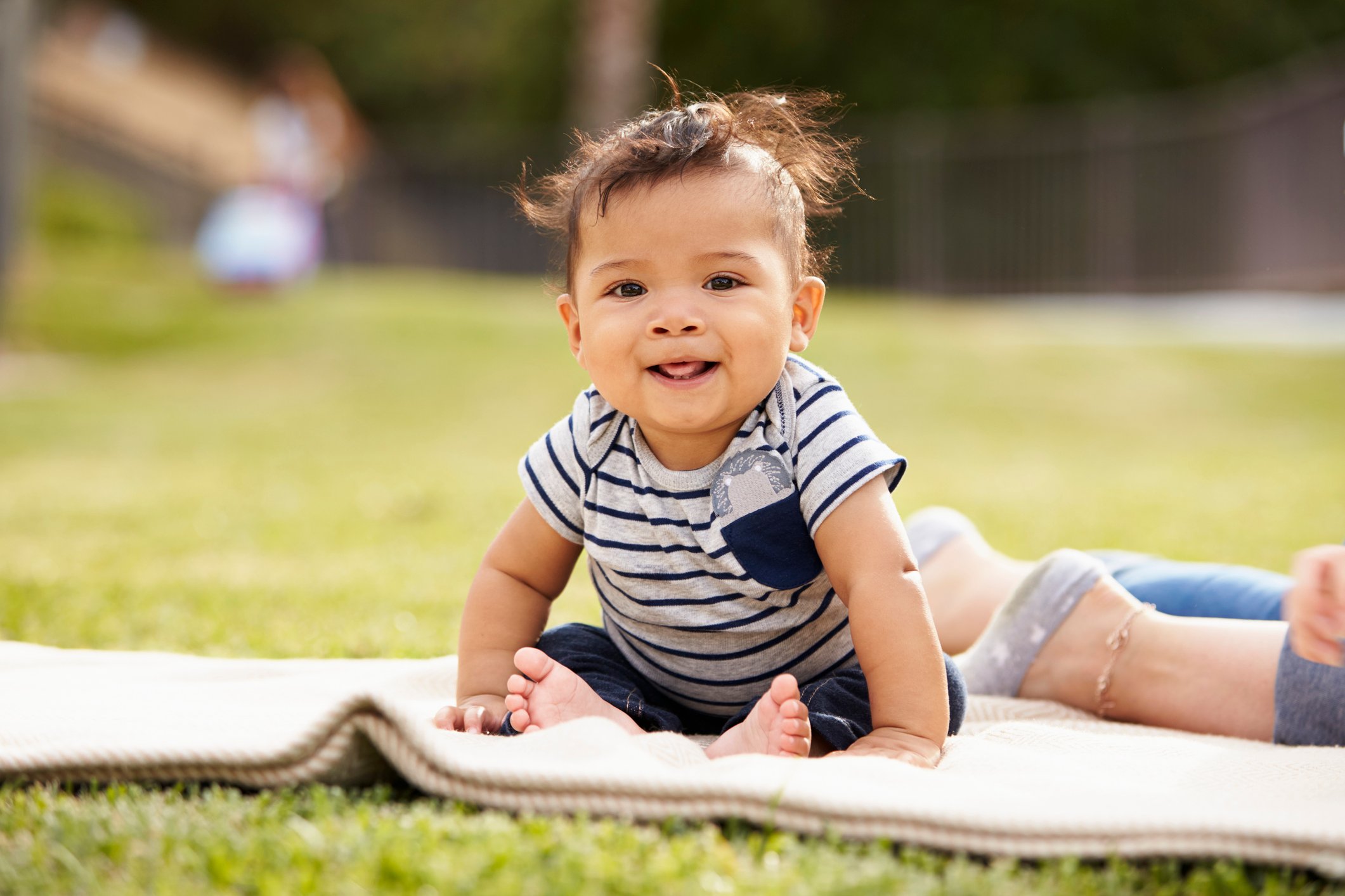 Little baby boy sitting up on a blanket in the park looking to camera, close up Little baby boy sitting up on a blanket in the park looking to camera, close up