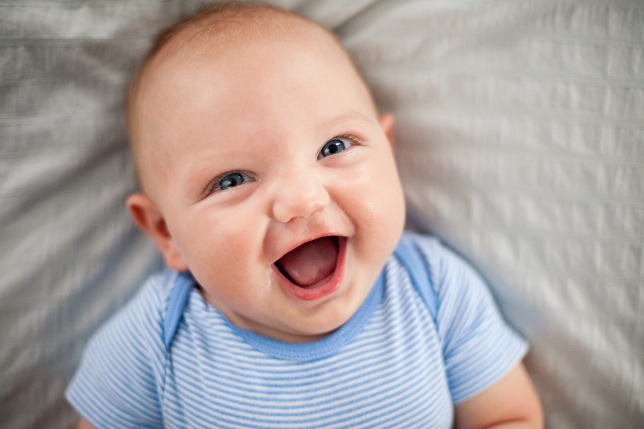Happy, Laughing Baby Boy Lying on Textured Fabric Happy, Laughing Baby Boy Lying on Textured Fabric